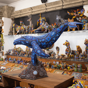 Escultura de ballena jorobada color azul sobre base color cafe cubierta con chaquiras