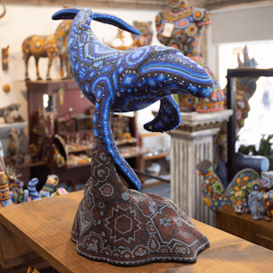 Escultura de ballena jorobada color azul sobre base color cafe cubierta con chaquiras