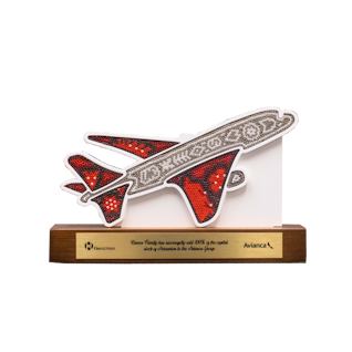 Wooden trophy in the shape of an airplane covered with beads on a wooden base