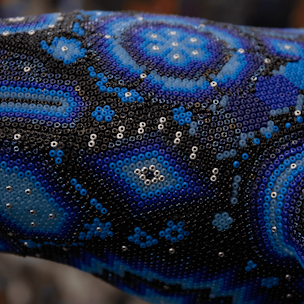 Blue humpback whale sculpture on a brown base covered with beads