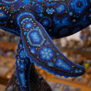 Blue humpback whale sculpture on a brown base covered with beads